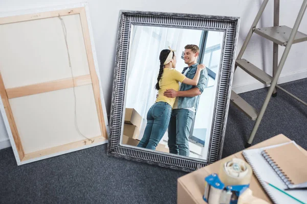 Espelho reflexo de jovem casal abraçando depois de se mudar para uma nova casa — Fotografia de Stock