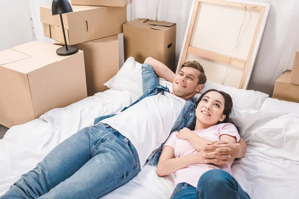 Beau jeune couple se détendre sur le lit après avoir déménagé dans une nouvelle maison — Photo de stock