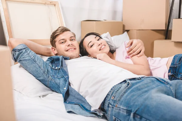 Hermosa pareja joven relajarse en la cama mientras se muda a un nuevo hogar - foto de stock