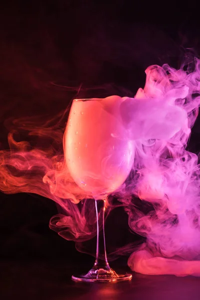 Glass full of pink smoke on black background — Stock Photo