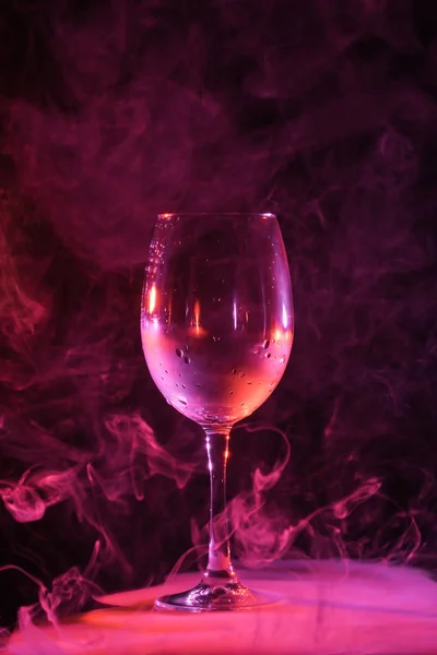 Verre vide avec fumée rose autour sur fond sombre — Photo de stock