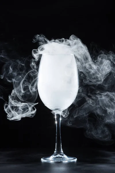 Wine glass with white smoke on black background — Stock Photo