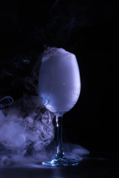 Wineglass with grey smoke on black background — Stock Photo