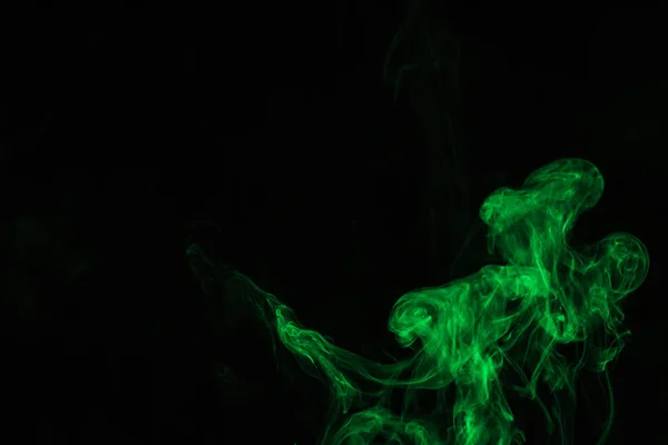 Kreativer schwarzer Hintergrund mit grünem Rauch — Stockfoto