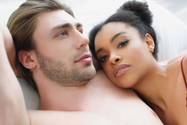 Retrato de jovem casal multiétnico apaixonado deitado na cama juntos de manhã — Fotografia de Stock