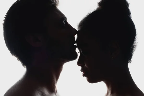 Vista lateral de silhuetas de casal interracial no amor — Fotografia de Stock