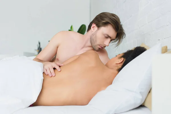 Partial view of multiethnic young couple in love in bed at home — Stock Photo