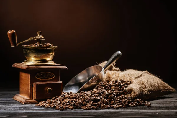 Coffee grinder with beans and scoop on rustic wooden table — Stock Photo