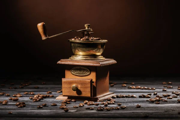 Kaffeemühle auf rustikalem Holztisch mit Kaffeebohnen verschüttet — Stockfoto