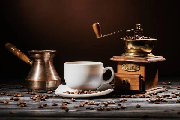 Nahaufnahme einer Tasse mit Cezve und Kaffeemühle auf rustikalem Holztisch — Stockfoto