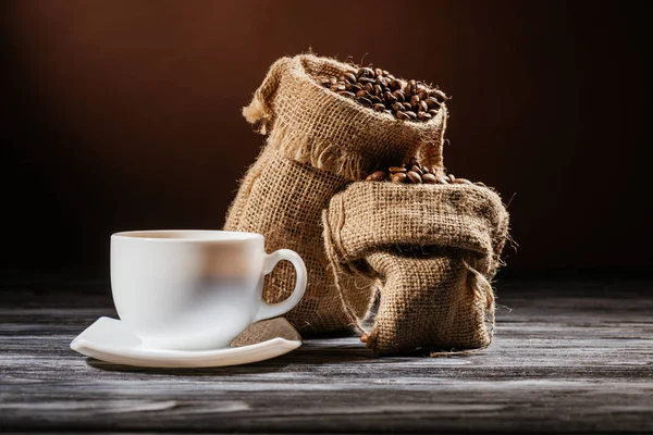 Nahaufnahme einer Tasse mit Kaffeesäcken auf einem rustikalen Holztisch — Stockfoto