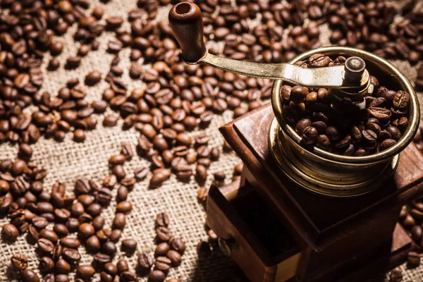 Close-up tiro de moedor de café em pano de saco derramado com grãos de café — Fotografia de Stock