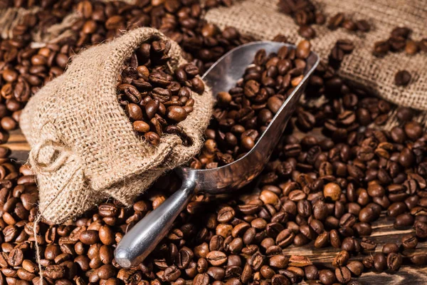 Grains de café torréfiés avec cuillère sur sac — Photo de stock