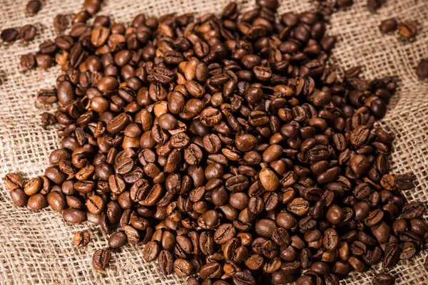 Primer plano de montón de granos de café tostados en tela de saco - foto de stock