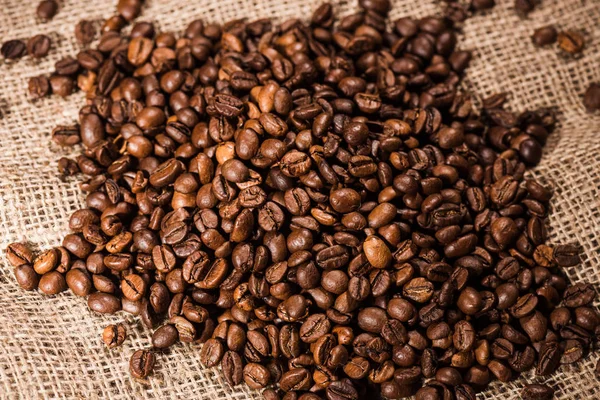 Close-up tiro de montão de grãos de café torrados em pano de saco — Fotografia de Stock