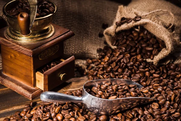 Close-up shot of vintage coffee grinder with scoop and sackcloth on rustic wooden table — Stock Photo