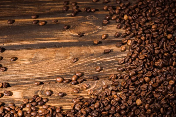 Vue de dessus des grains de café torréfiés renversés sur la table en bois rustique — Photo de stock