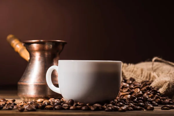 Plan rapproché de tasse de café avec des grains torréfiés et cezve vintage — Photo de stock