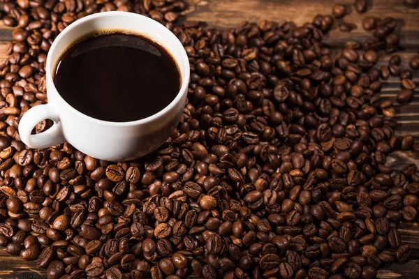 Vista ad angolo alto di tazza con chicchi di caffè su tavolo in legno rustico — Foto stock