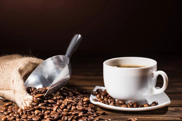 Nahaufnahme Haufen Kaffeebohnen Tasse und Metallschaufel auf rustikalem Holztisch — Stockfoto