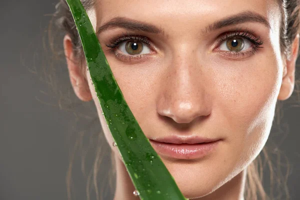 Menina com pele limpa perfeita segurando folha de aloés fresco verde, isolado em cinza — Fotografia de Stock