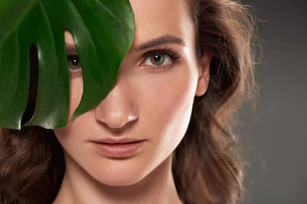 Attraente ragazza pura con foglia di monstera, isolato su grigio — Foto stock