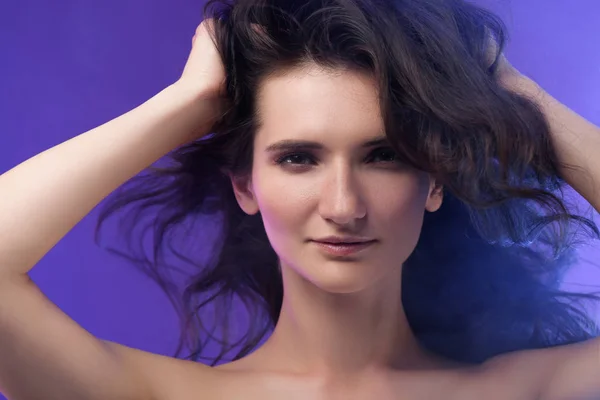 Portrait of young beautiful brunette woman on purple — Stock Photo