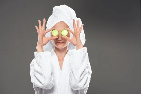 Fille avec des tranches de concombre en peignoir blanc et serviette sur la tête, isolé sur gris — Photo de stock