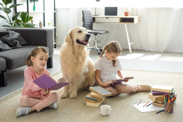 Irmãzinhas lendo livros com cão golden retriever perto de casa — Fotografia de Stock