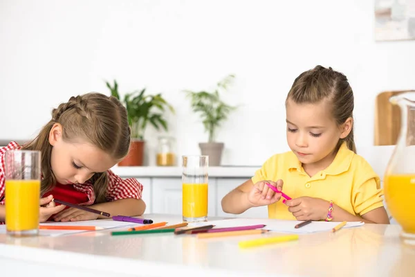 Retrato de lindos niños pequeños dibujando cuadros en la mesa en casa - foto de stock