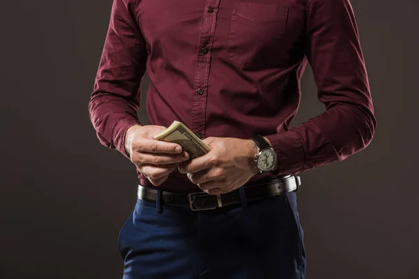 Cropped shot of man holding dollar banknotes isolated on black — Stock Photo