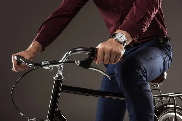 Cropped shot of young man riding bicycle on black — Stock Photo