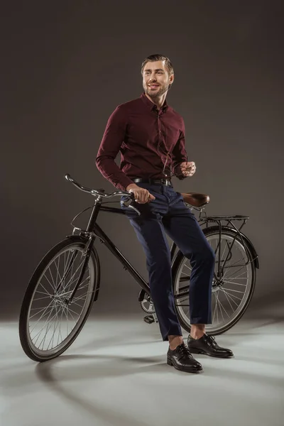 Повнометражний красень усміхнений молодий чоловік сидить на велосипеді і дивиться в очі на чорний — стокове фото