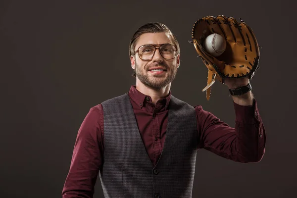 Handsome smiling buisnesssman in eyeglasses holding ball with baseball glove isolated on black — Stock Photo