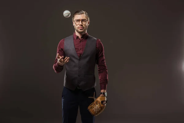 Homme d'affaires sérieux avec gant de baseball lancer balle et regarder la caméra isolé sur noir — Photo de stock