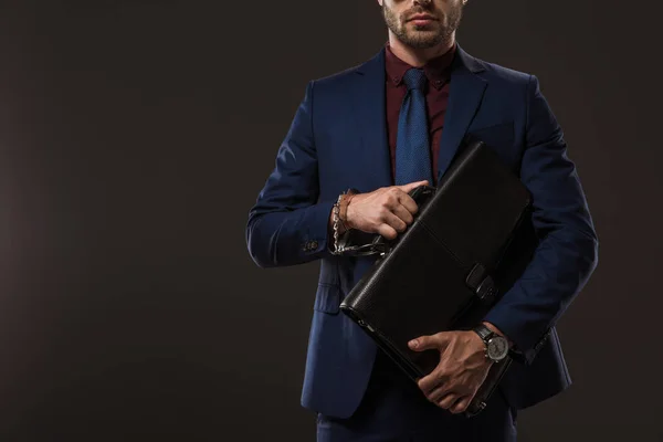 Обрізаний знімок бізнесмена в наручниках, що тримає портфель ізольовано на чорному — стокове фото