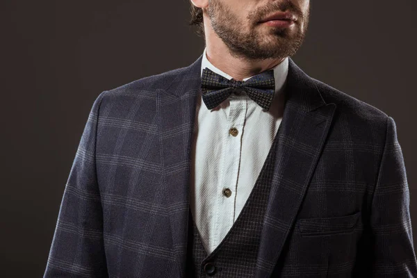 Cropped shot of stylish man wearing suit and bow tie isolated on black — Stock Photo