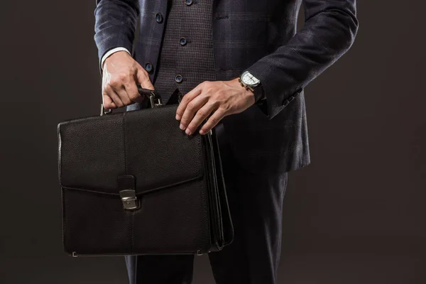 Cropped shot of businessman holding briefcase isolated on black — Stock Photo