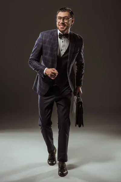 Schöner lächelnder Geschäftsmann mit Aktentasche und läuft auf schwarz — Stockfoto