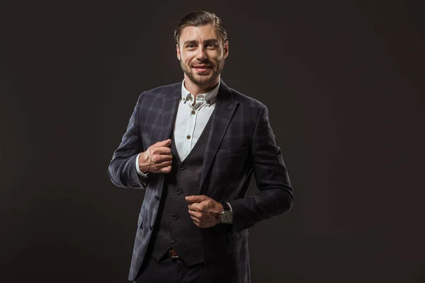 Portrait of handsome stylish man in formal wear smiling at camera isolated on black — Stock Photo