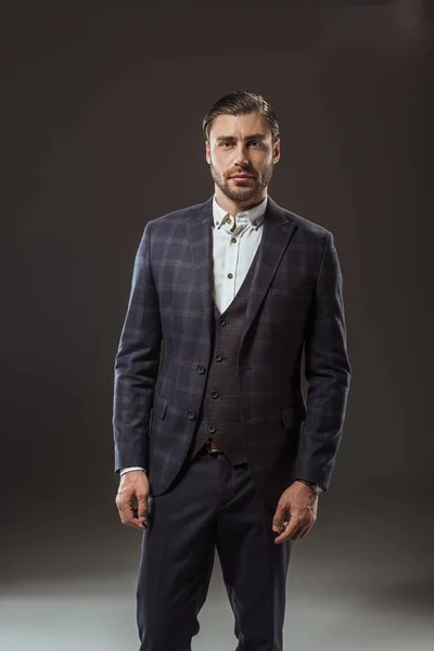 Portrait of handsome man in fashionable suit looking at camera on black — Stock Photo