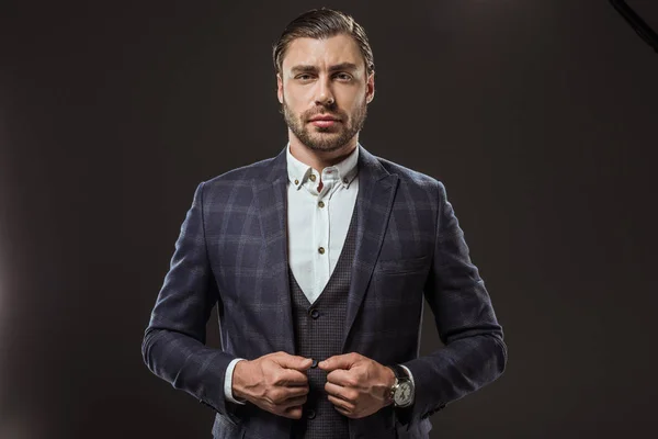 Portrait of handsome young man in stylish suit looking at camera isolated on black — Stock Photo