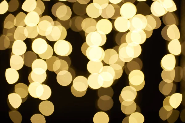 Beautiful golden shiny defocused bokeh on black background — Stock Photo