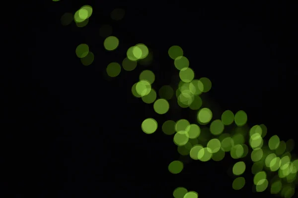 Schöne glänzende grüne defokussierte Bokeh auf schwarzem Hintergrund — Stockfoto