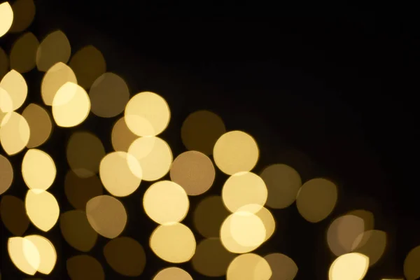 Beautiful golden shiny defocused bokeh on black background — Stock Photo