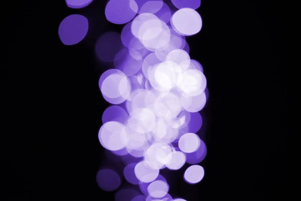 Bonito brilhante desfocado violeta bokeh no fundo preto — Fotografia de Stock