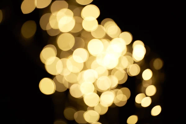 Beautiful shiny defocused golden bokeh on black background — Stock Photo