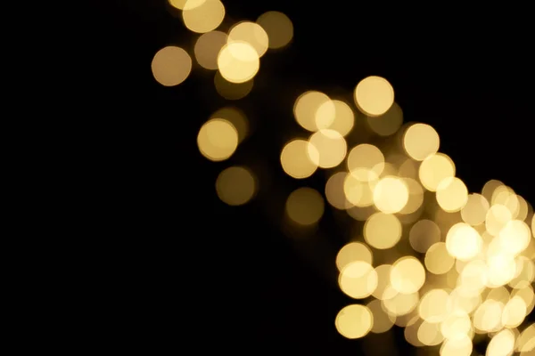 Beautiful shiny defocused golden bokeh on black background — Stock Photo