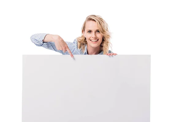 Sonriente atractiva mujer apuntando en blanco cartel aislado en blanco — Stock Photo