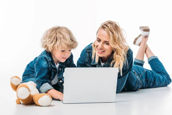 Madre e hijo usando el ordenador portátil en el suelo en blanco - foto de stock